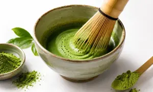 Przygotowanie idealnego naparu matcha: zielony proszek, bambusowa miotełka i miseczka z pianką.