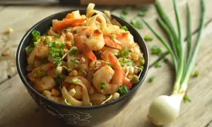 Pyszny pad thai z krewetkami, posypany szczypiorkiem i orzeszkami. Idealny przepis na szybki obiad.