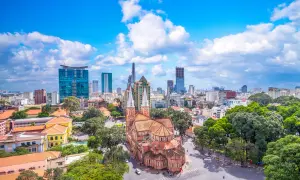 Piękna pogoda w Ho Chi Minh: katedra Notre Dame i nowoczesne wieżowce na tle błękitnego nieba z chmurami.