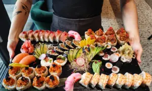Ogromna taca z różnorodnym jedzeniem sushi: rolki z łososiem, tuńczykiem, krewetkami, a także nigiri i sashimi.