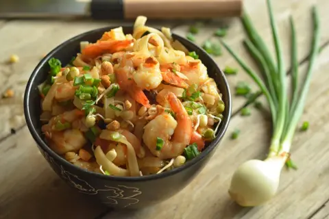 Pyszny pad thai z krewetkami, posypany szczypiorkiem i orzeszkami. Idealny przepis na szybki obiad.