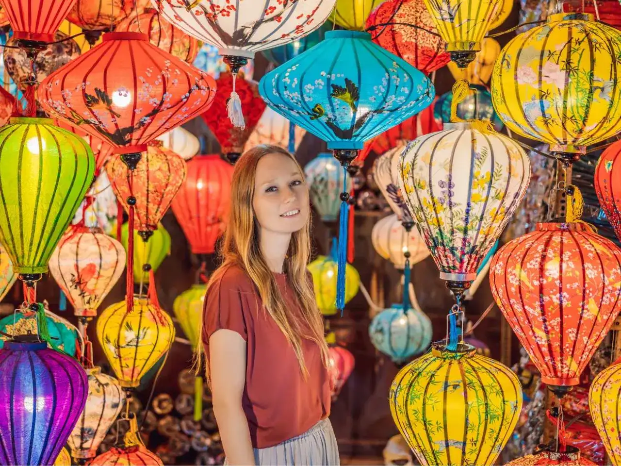 Kobieta wśród kolorowych lampionów, tworzących magiczną atmosferę wietnamskiego Nowego Roku.