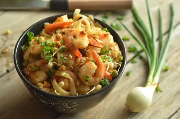 Pyszny pad thai z krewetkami, posypany szczypiorkiem i orzeszkami. Idealny przepis na szybki obiad.